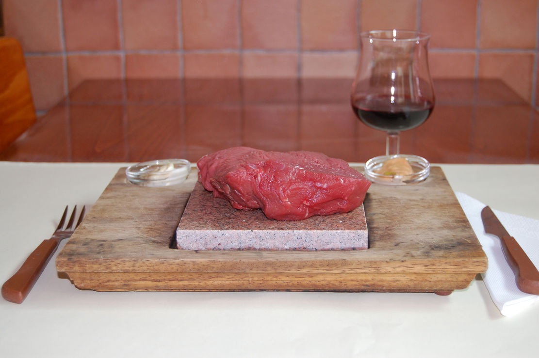 Carne sobre pedra, acompanhada por vinho, na Adega das Gravatas